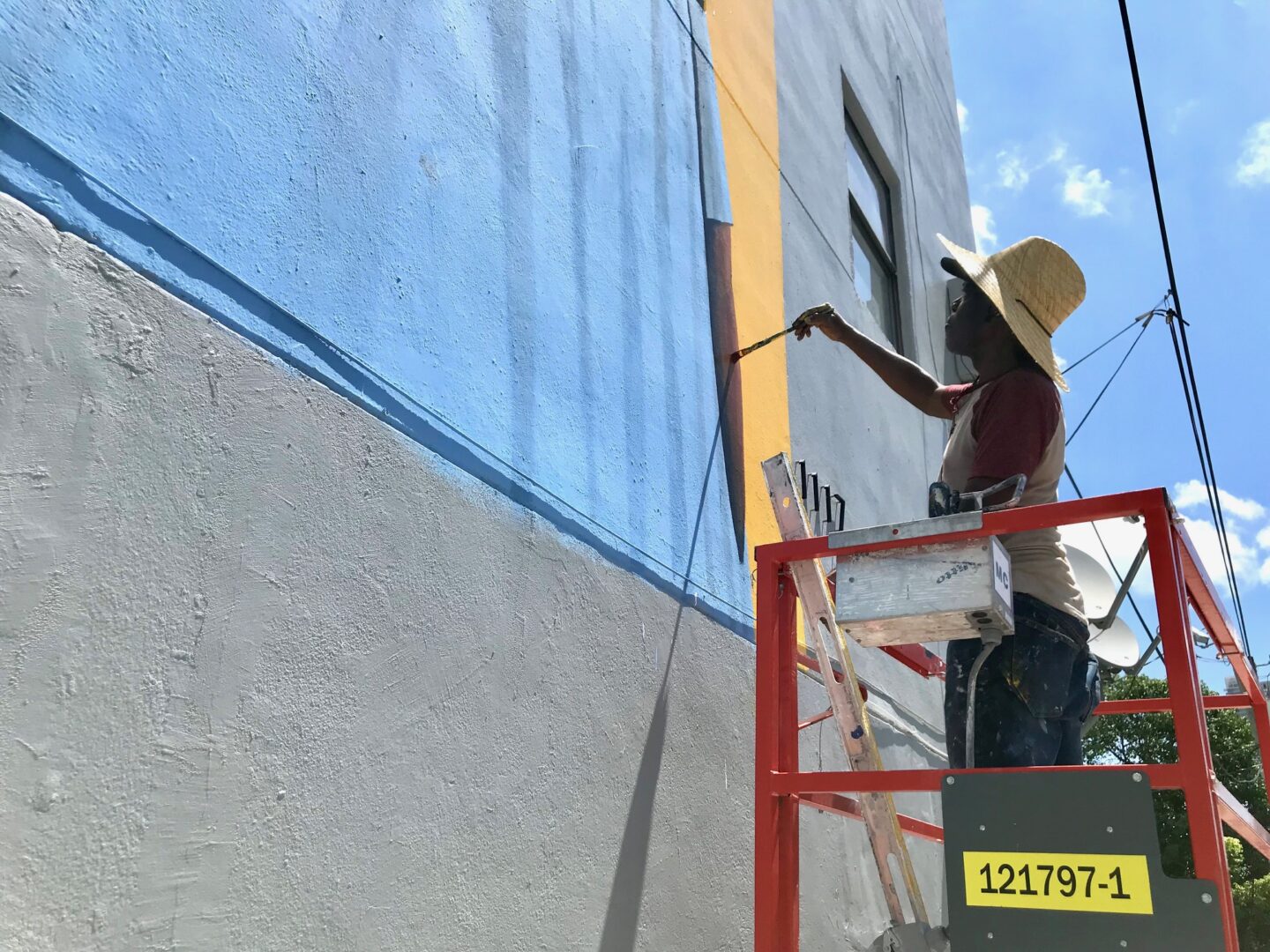 A person on a ladder painting a building.