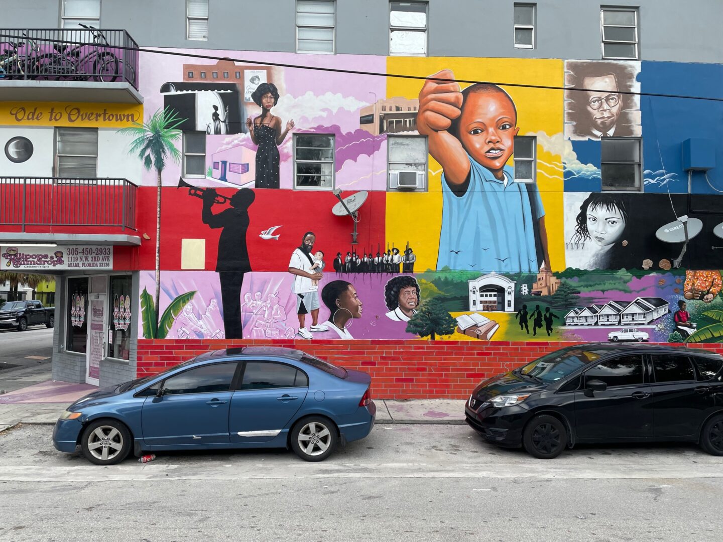 A car parked in front of a building with many different pictures on it.