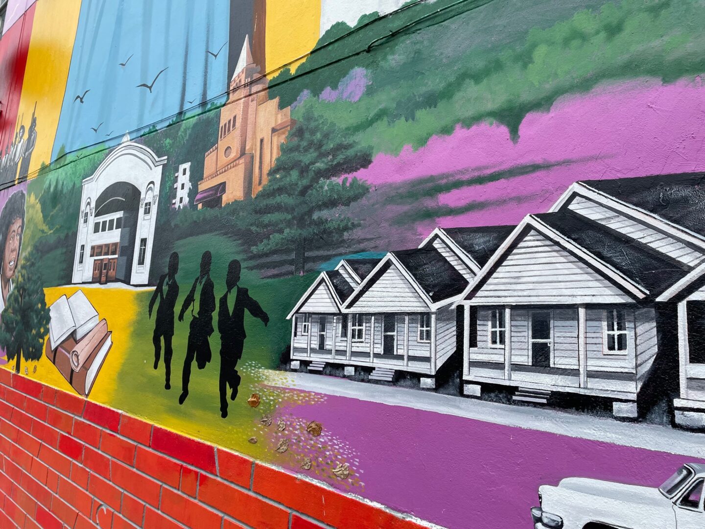 A mural of houses and people walking on the sidewalk.