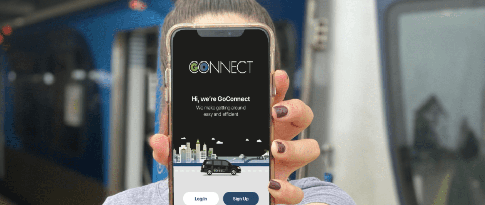 A woman holding up her phone in front of a train.