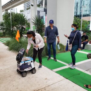 A woman is pushing a robot dog on the sidewalk.