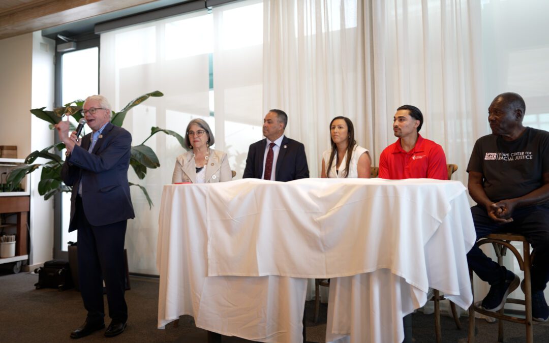 A group of people sitting at a table with a man standing next to them.