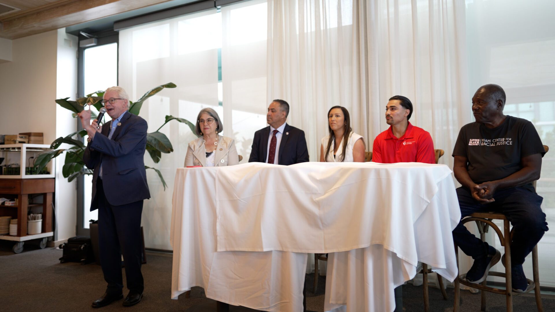 A group of people sitting at a table with a man standing next to them.