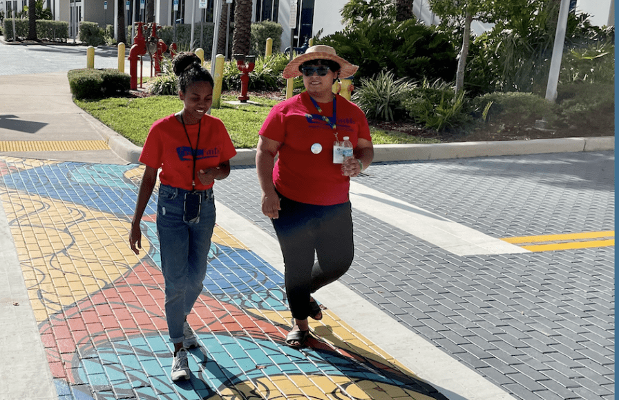 Two women walking on colorful crosswalk.