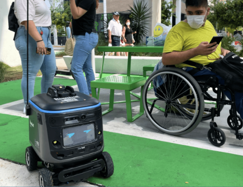 Delivery robot near a man in a wheelchair.